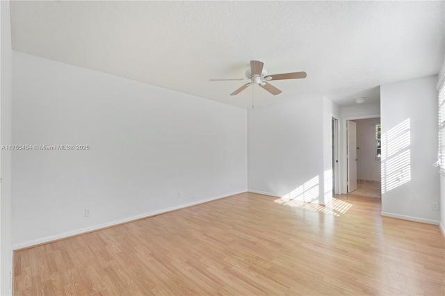 unfurnished room featuring light wood-style flooring, a textured ceiling, baseboards, and a ceiling fan