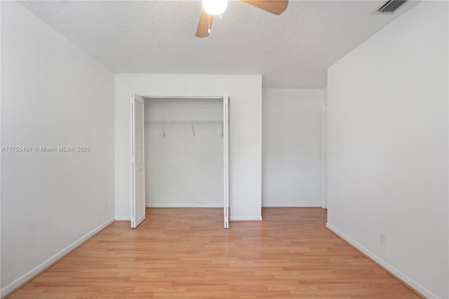 unfurnished bedroom featuring light wood finished floors, baseboards, visible vents, a textured ceiling, and a closet