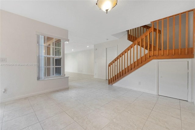 tiled empty room featuring stairway and baseboards