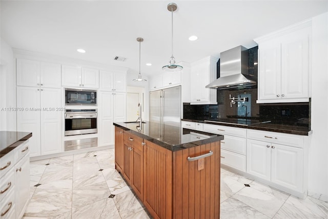 kitchen with built in appliances, a sink, marble finish floor, backsplash, and wall chimney exhaust hood