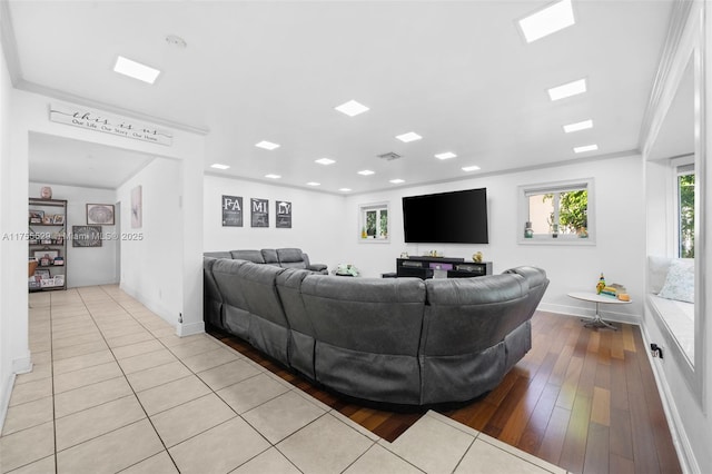 living room with ornamental molding, visible vents, baseboards, and wood finished floors