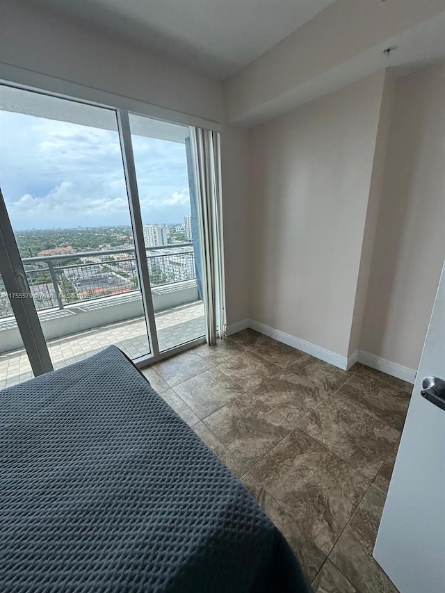 bedroom with access to outside, baseboards, and a city view