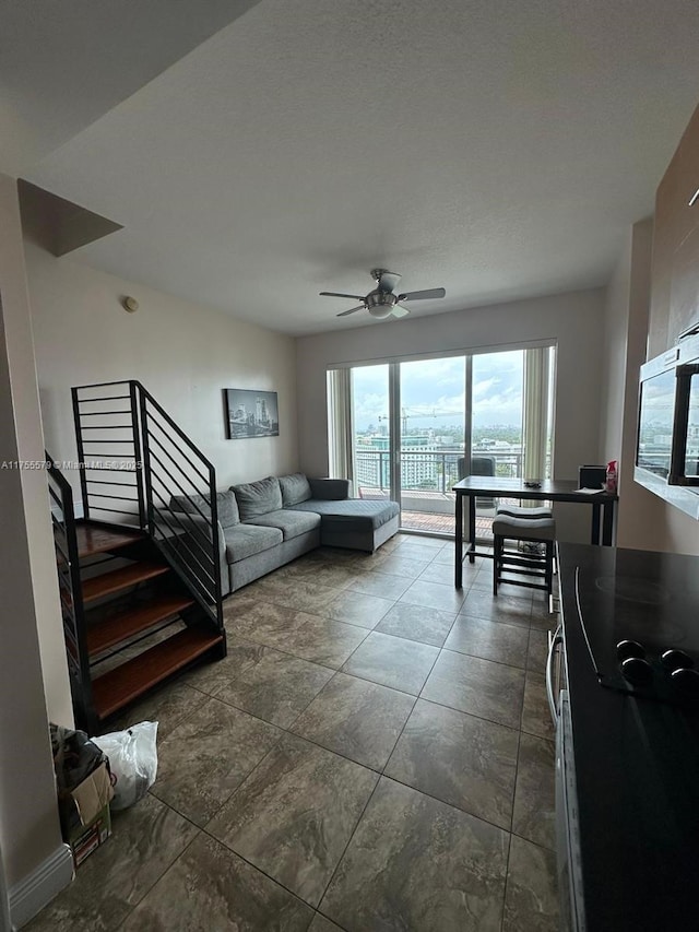 living room with a ceiling fan and stairs