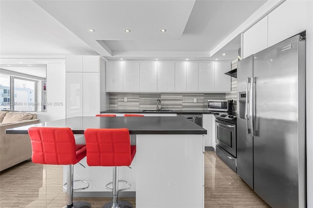 kitchen with stainless steel appliances, modern cabinets, a sink, and white cabinetry