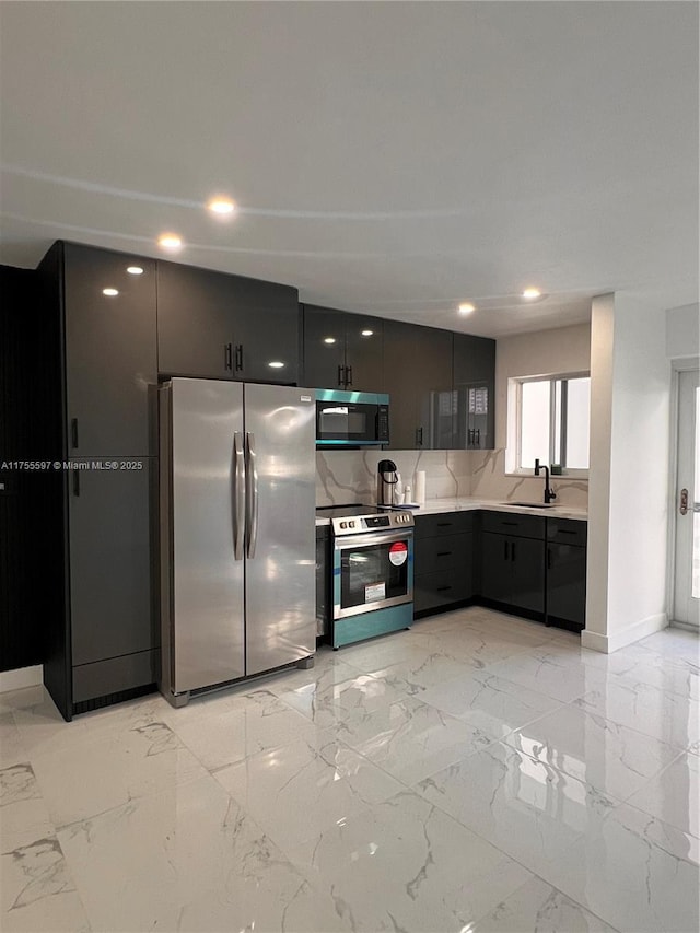 kitchen with decorative backsplash, appliances with stainless steel finishes, marble finish floor, light countertops, and a sink