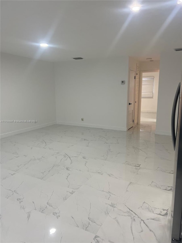 spare room with marble finish floor and baseboards