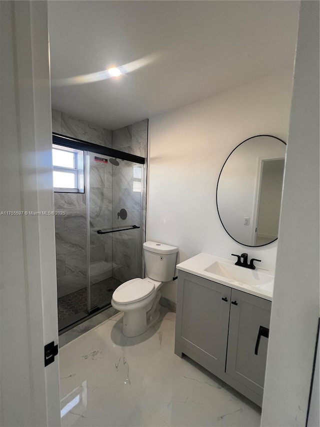 full bathroom featuring toilet, marble finish floor, a stall shower, and vanity