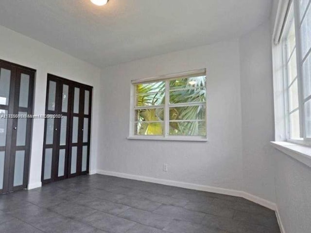 unfurnished room featuring french doors and baseboards