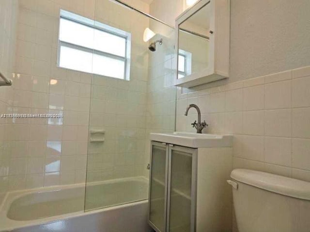 full bath with toilet, bathing tub / shower combination, vanity, and tile walls