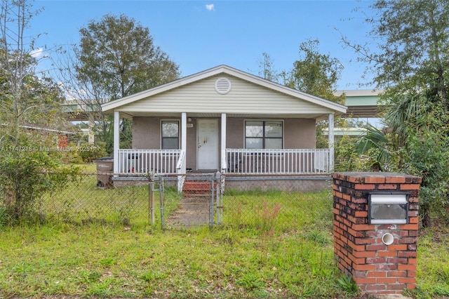 view of front facade with a fenced front yard, stucco siding, covered porch, a gate, and a front lawn