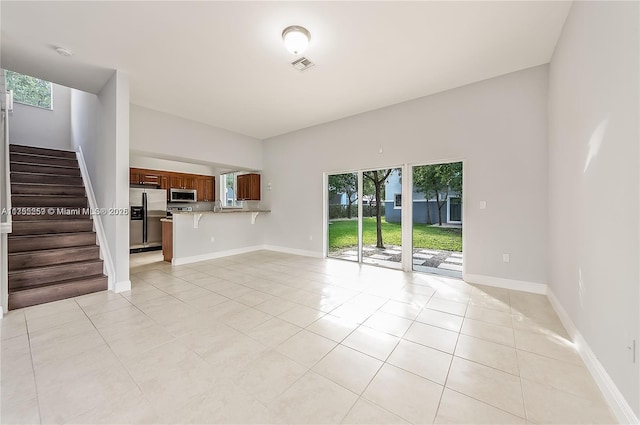 unfurnished living room featuring visible vents, light tile patterned flooring, stairway, and baseboards