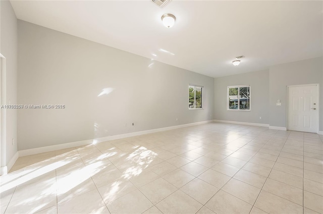 unfurnished room featuring light tile patterned flooring, vaulted ceiling, and baseboards