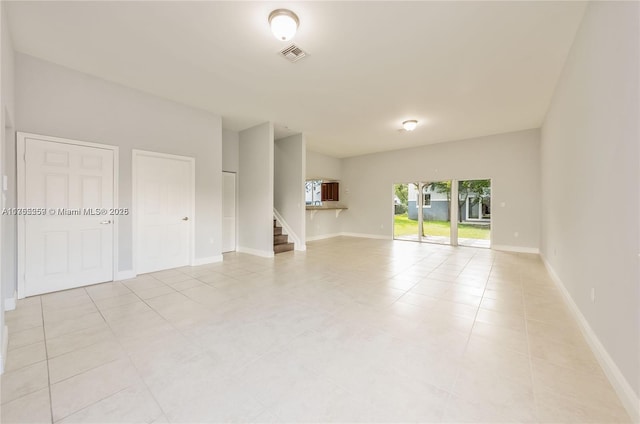 unfurnished living room featuring stairway, baseboards, visible vents, and light tile patterned flooring