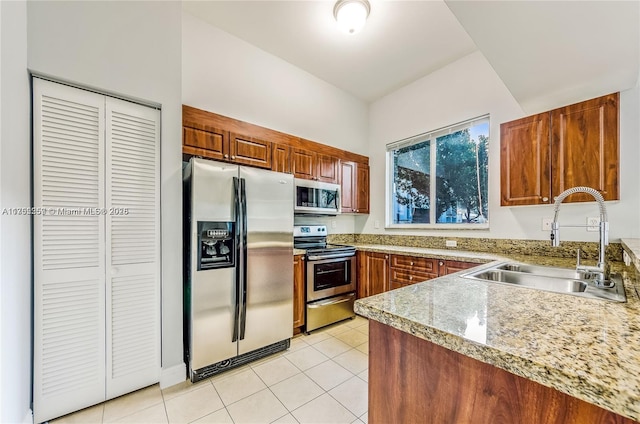 kitchen with appliances with stainless steel finishes, brown cabinets, a sink, and light tile patterned floors