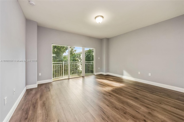 spare room featuring baseboards and wood finished floors