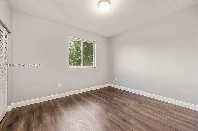 unfurnished bedroom featuring a closet, baseboards, and dark wood-type flooring