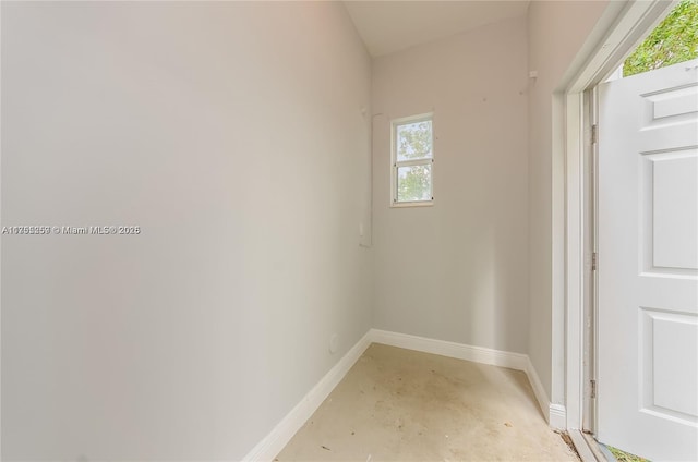 empty room with unfinished concrete flooring and baseboards