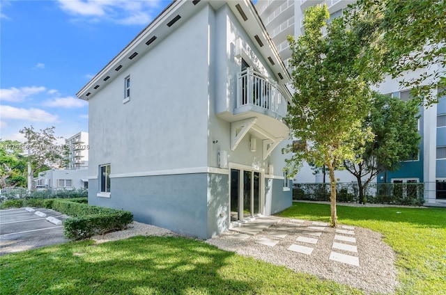 view of home's exterior featuring fence, a lawn, and stucco siding