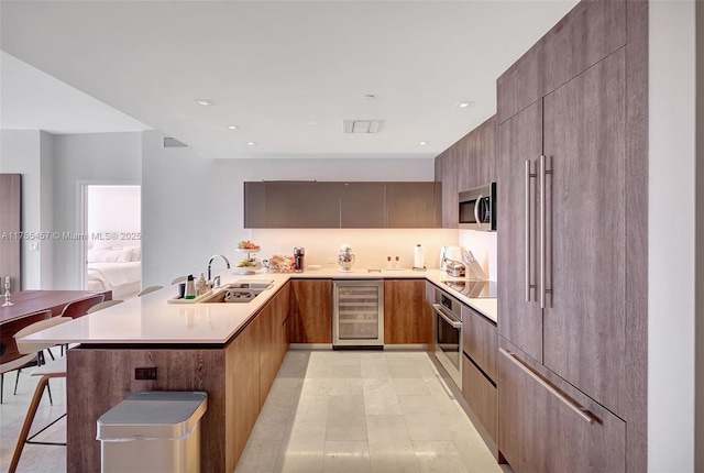 kitchen featuring wine cooler, stainless steel appliances, a peninsula, a sink, and modern cabinets