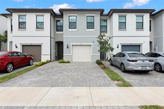 view of property with decorative driveway, an attached garage, and stucco siding