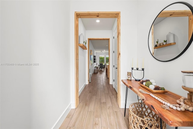 hall with light wood finished floors and baseboards