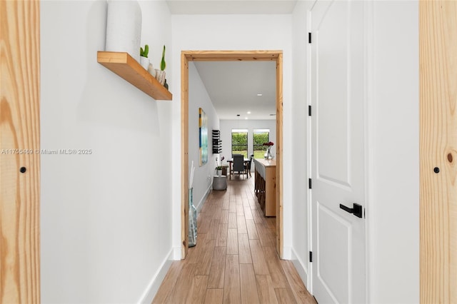 hall featuring light wood-type flooring and baseboards