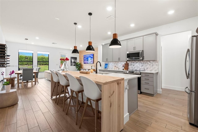 kitchen featuring visible vents, appliances with stainless steel finishes, a sink, gray cabinetry, and backsplash