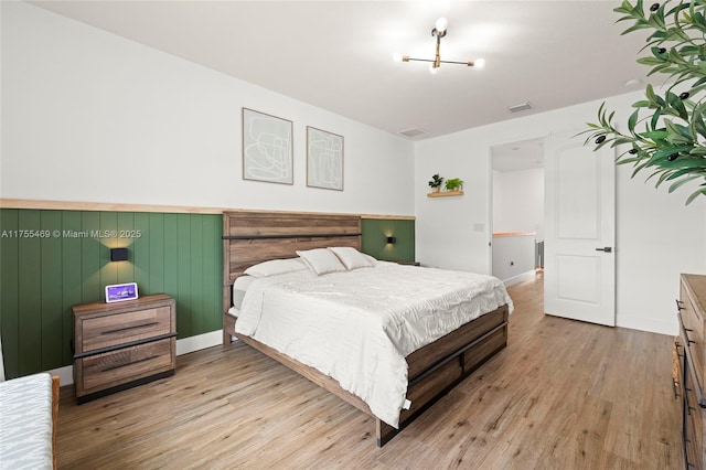 bedroom with wood finished floors, visible vents, and baseboards