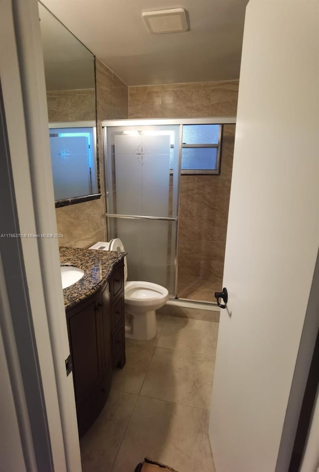 full bath featuring toilet, a stall shower, tile patterned flooring, and vanity