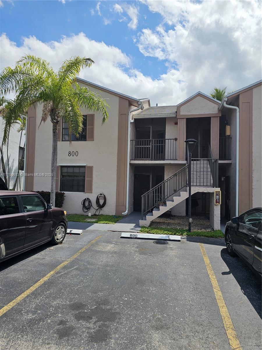 view of property with stairway and uncovered parking