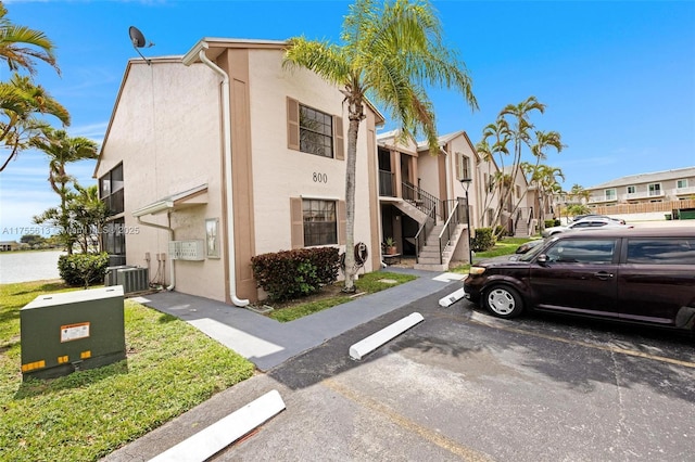 view of property with cooling unit, a residential view, uncovered parking, and stairs