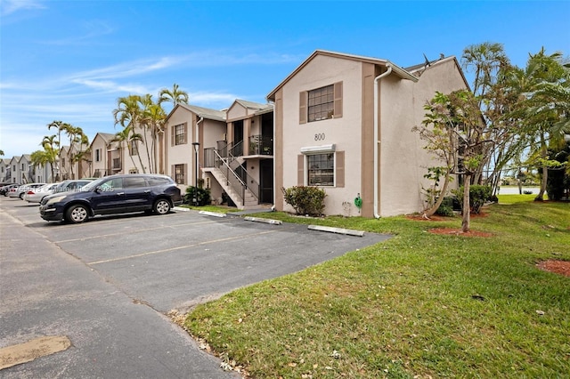 view of building exterior featuring a residential view, stairs, and uncovered parking
