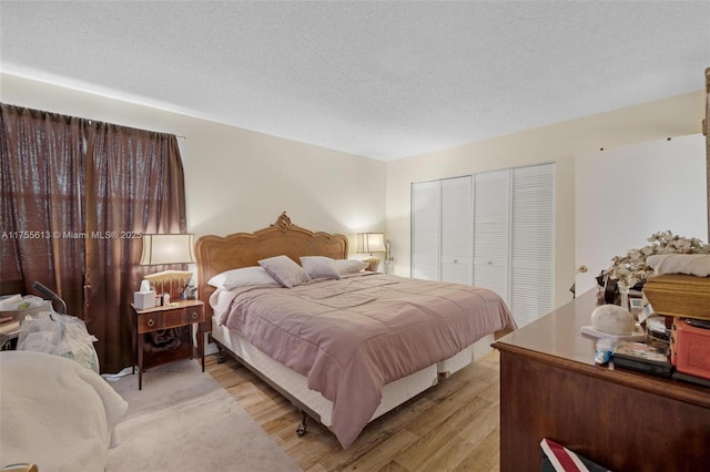 bedroom featuring light wood-type flooring, a closet, and a textured ceiling