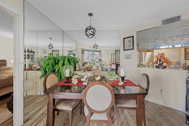 dining area featuring visible vents, baseboards, and wood finished floors
