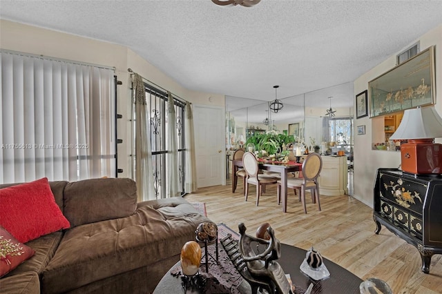 living room featuring wood finished floors, visible vents, and a textured ceiling