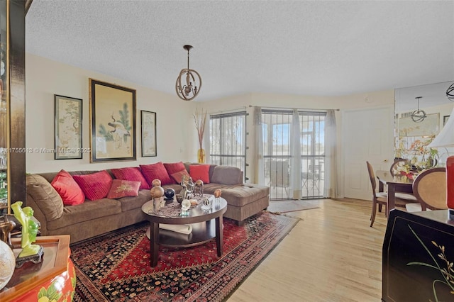 living area featuring a notable chandelier, a textured ceiling, and light wood-type flooring