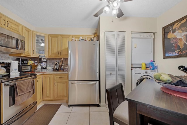 kitchen with a ceiling fan, appliances with stainless steel finishes, light countertops, light tile patterned floors, and decorative backsplash