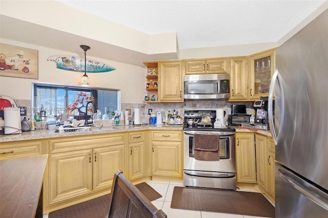 kitchen featuring glass insert cabinets, light tile patterned floors, decorative backsplash, appliances with stainless steel finishes, and a sink
