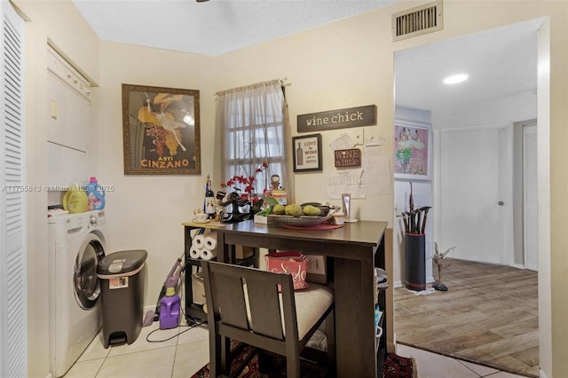 dining area with visible vents, a textured ceiling, light tile patterned flooring, stacked washer / drying machine, and baseboards