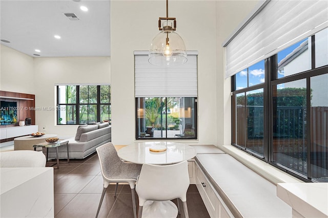 dining area featuring tile patterned flooring, a high ceiling, visible vents, and a wealth of natural light