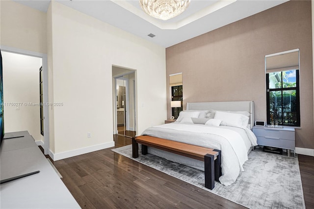 bedroom featuring dark wood-type flooring, visible vents, a notable chandelier, and baseboards