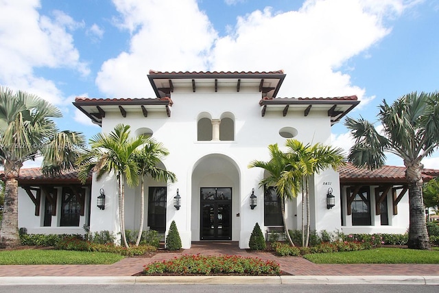 mediterranean / spanish house with french doors, a tile roof, and stucco siding