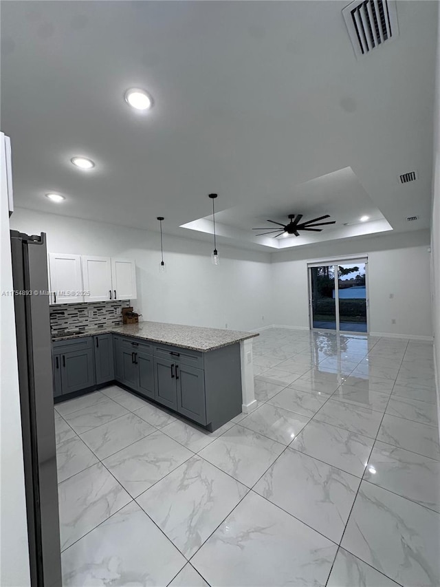 kitchen featuring marble finish floor, visible vents, a raised ceiling, and a ceiling fan