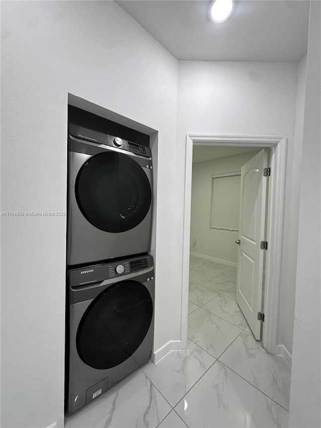 washroom with marble finish floor, baseboards, laundry area, and stacked washer and clothes dryer