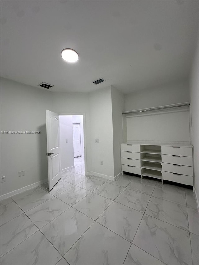 unfurnished bedroom with marble finish floor, baseboards, and visible vents