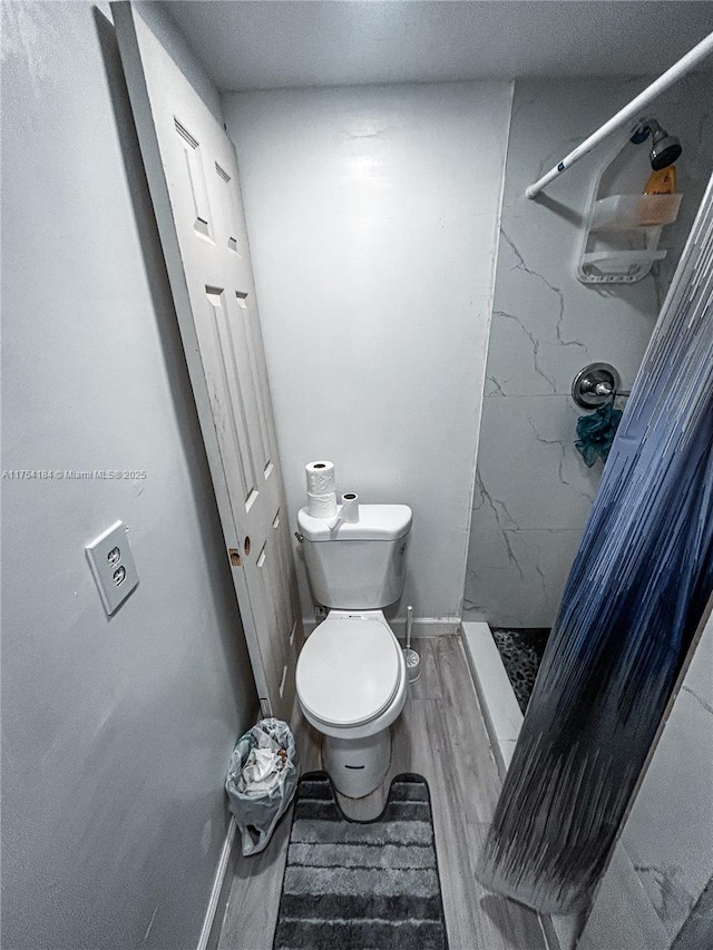 full bath with a stall shower, baseboards, toilet, and wood finished floors