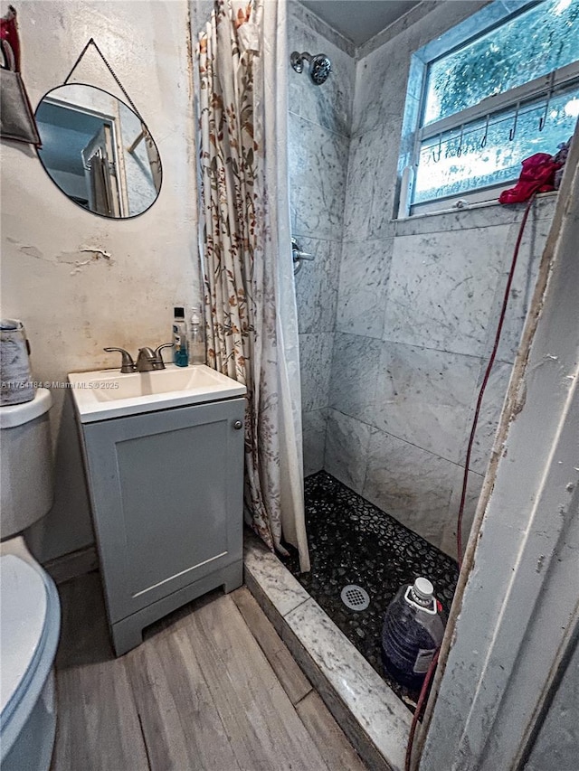 bathroom with vanity, a stall shower, wood finished floors, and toilet