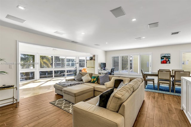 living area featuring recessed lighting, visible vents, and wood finished floors