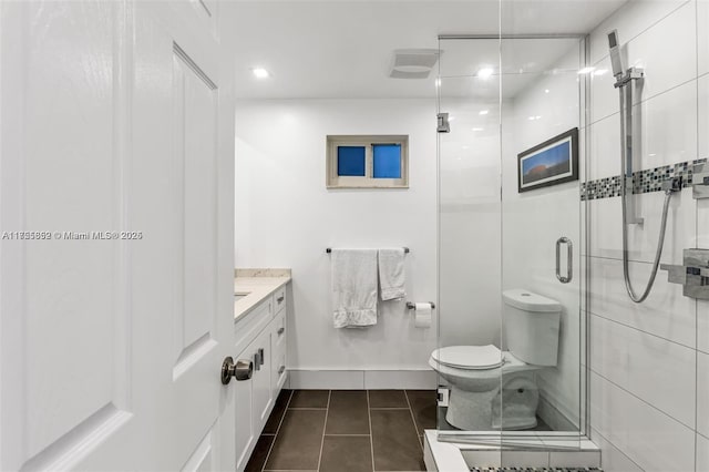 bathroom featuring toilet, a stall shower, vanity, baseboards, and tile patterned floors