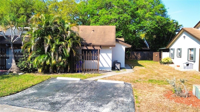 view of front of property with uncovered parking, fence, a front lawn, and stucco siding